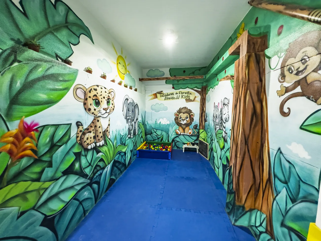 Espaço Kids pintado de floresta, com piscina de bolinhas