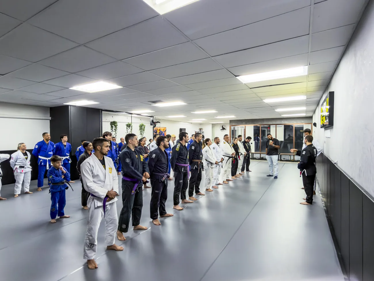 Turma perfilada no tatame no início da aula